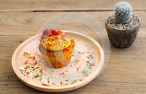 Yellow cupcakes put on a spherical wooden plate. Sprinkled with topping many colors