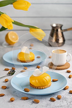 Yellow cupcakes and cup of coffee with yellow tulips on concrete background. Tasty morning dessert