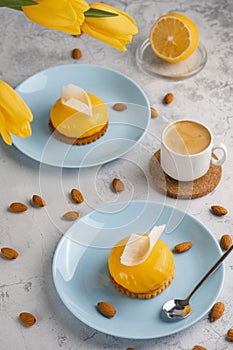 Yellow cupcakes and cup of coffee with yellow tulips on concrete background. Tasty morning dessert