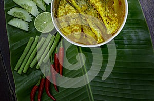 Yellow curry snapper fish with Lotus Stems, Southern Thai Spicy food and fresh vegetable in white dish on banana leaf/selective