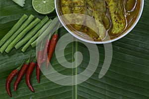 Yellow curry snapper fish with Lotus Stems, Southern Thai Spicy food and fresh vegetable in white dish on banana leaf / selective.