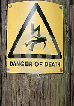 Yellow danger of death sign on wooden post