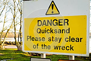 Yellow Danger Quicksand, please say clear of the wreck sign on a tree