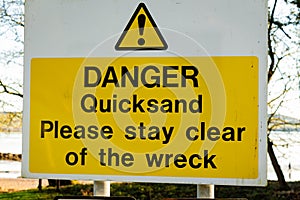 Yellow Danger Quicksand, please say clear of the wreck sign on a tree