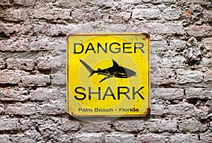 Yellow Danger Shark sign on brick wall