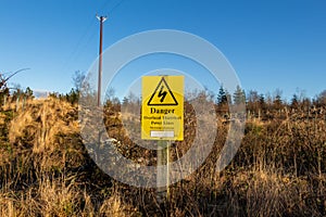 Yellow danger sign warning of overhead electrical power lines and risk of death