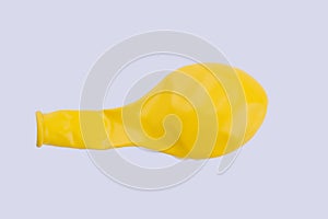 Yellow deflated balloon on white background.