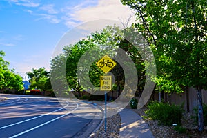 Yellow diamond shaped warning road sign with bicycle symbol and 'Share the road' text along empty curved road