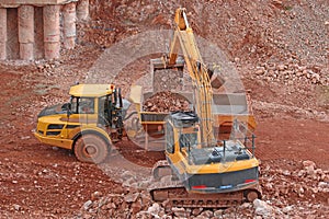 Yellow digger loading a dump truck