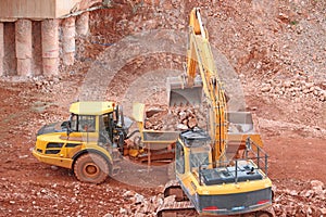 Yellow digger loading a dump truck