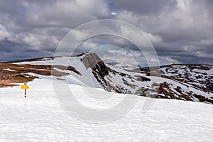 Yellow directional path mark in form of arrow buried in deep snow near Ladinger Spitz, Saualpe, Carinthia, Styria, Austria