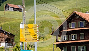 Yellow directional road signs. Wooden house in the background.