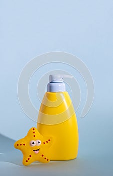 Yellow dispenser bottle of a children's cosmetic product with a place for a logo and funny rubber toy. Baby sun