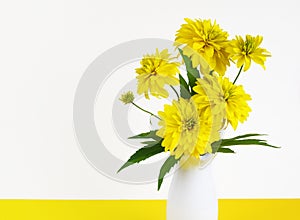 Yellow dissected rudbeckia flowers in a white vase