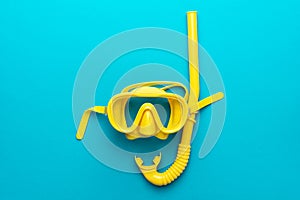 Yellow diving mask and snorkel over blue background with central composition