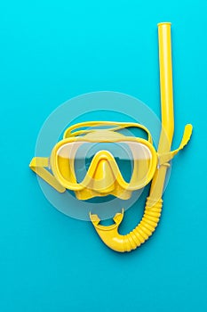 Yellow diving mask and snorkel over blue background with central composition