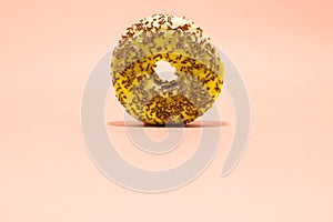 Yellow donut with chocolate crumbs on light pink background