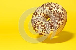 Yellow donut with chocolate crumbs on yellow background.