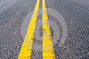 Yellow double dividing line over black highway asphalt