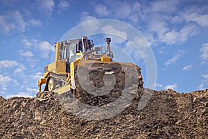 Yellow dozer pushes a pile of sand