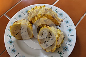 Yellow dragon fruit, sliced and whole, on a floral plate