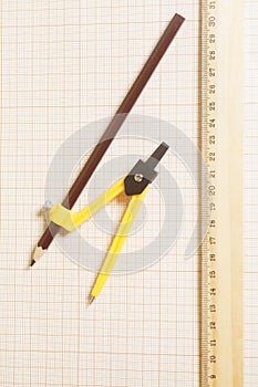 Yellow Drawing compass with black pencil and ruler on graph