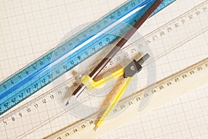 Yellow Drawing compass with black pencil and rulers on graph pap