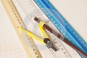 Yellow Drawing compass with black pensil and rulers on graph