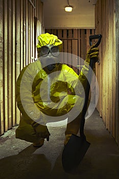 Yellow dressed man in chemical style overall with gasmask and shovel