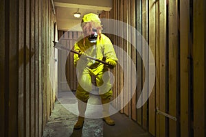 Yellow dressed man in chemical style overall with gasmask and shovel