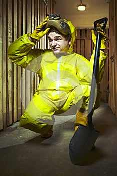 Yellow dressed man in chemical style overall with gasmask and shovel