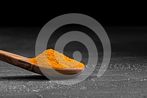 Yellow dried ground turmeric spice in the wooden spoon