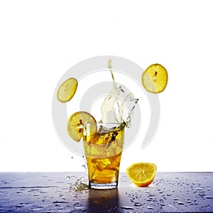 Yellow drink with splash, ice cubes and flying lemons slices, re