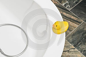 Yellow duck on corner of round bathtub in luxury stone