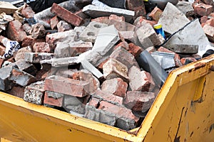 Yellow dumpster skip full of masonry waste