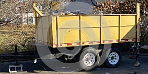 Yellow dumpster on a trailer in a driveway