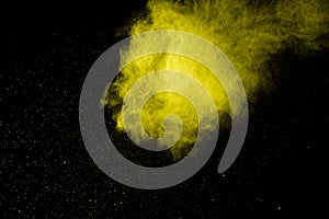 Yellow dust particles explosion on black background.Yellow powder  splash