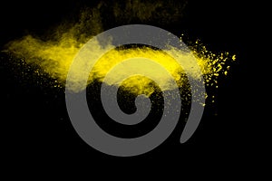 Yellow dust particles explosion on black background.Yellow powder  splash