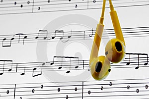 yellow earphones above content of music notes background on a computer laptop screen