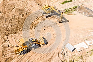 Yellow earthmover and excavator doing ground works during road construction