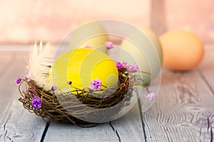 Yellow Easter egg in bird's nest, eggs with flowers. Spring holiday composition.