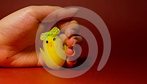 Yellow easter toy chisken in woman hand, easter chicken in hand, red background