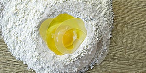 A yellow egg is smashed in a heap of flour