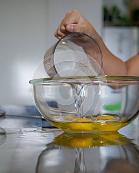 Yellow egg yolks in a clear transparent bowl. Mixing with oil to make a cake
