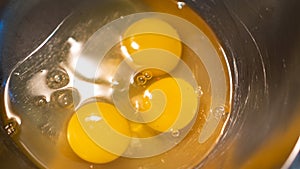 Yellow eggs on metallic bowl. Three chicken egg yolks. Preparation for scrambled eggs in a metal bowl. Cooking eggs