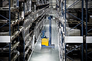 Yellow electric forklift reach truck on the background of a discolored warehouse