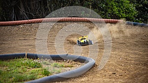 Yellow electric RC buggy racing on an offroad outdoor track