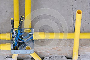 yellow eletric light system PVC tube install square hub iron box on concrete raw wall for building in house site. fixing pipe for