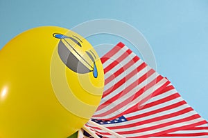 Yellow emoji balloons with American flags on a blue background.