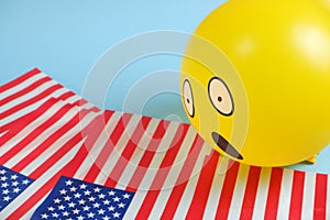 Yellow emoji balloons with American flags on a blue background.